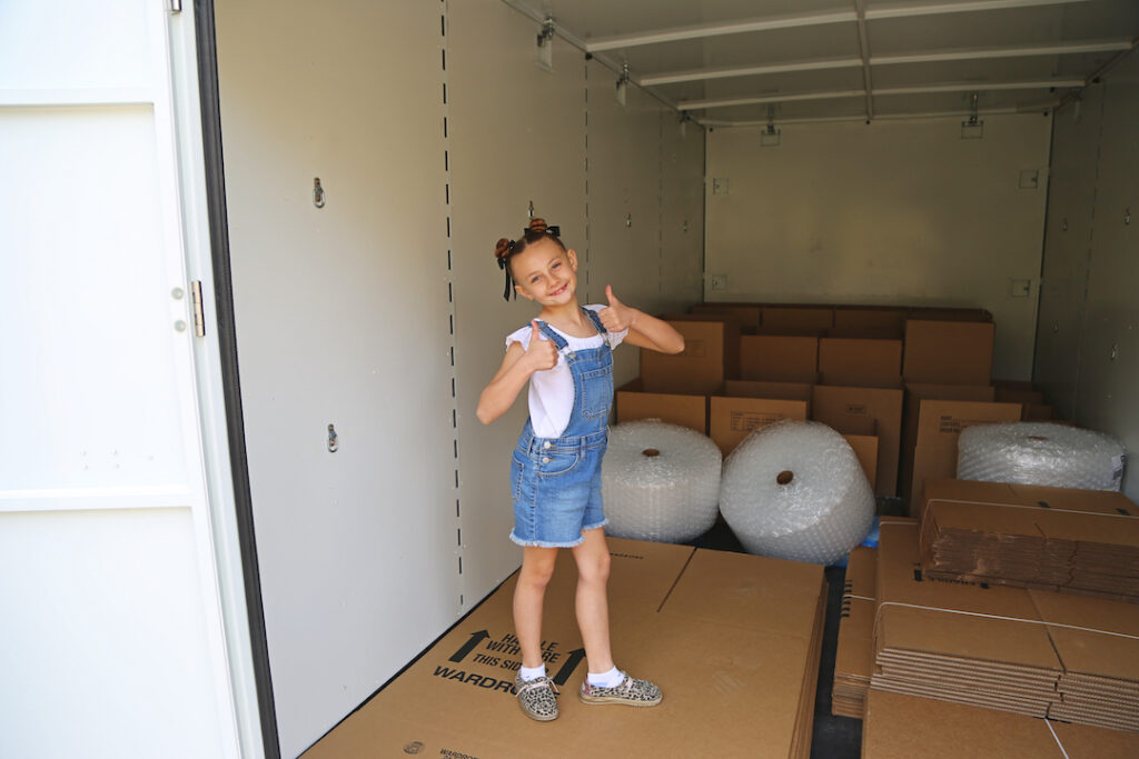 How to Choose the Right Storage Container: Your Guide Little girl standing in storage unit helping her mother move from one house to another